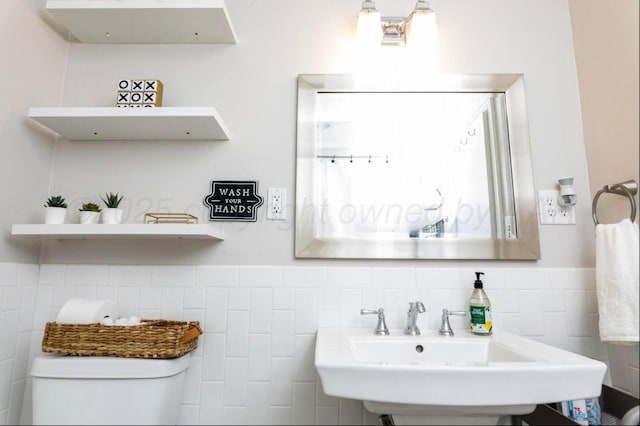 2406 Anna St, Amarillo, TX 79106 - bathroom featuring toilet, a sink, tile walls, and a wainscoted wall