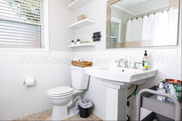 2406 Anna St, Amarillo, TX 79106 - bathroom with tile walls, toilet, healthy amount of natural light, wainscoting, and ornamental molding