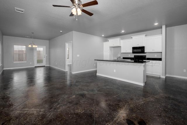 kitchen featuring a kitchen island with sink, white cabinetry, black microwave, dark countertops, and open floor plan