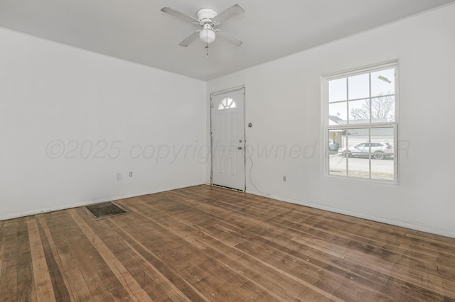 spare room featuring wood-type flooring, visible vents, and a ceiling fan