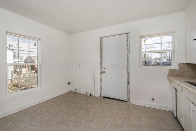 interior space featuring crown molding, light tile patterned floors, and baseboards