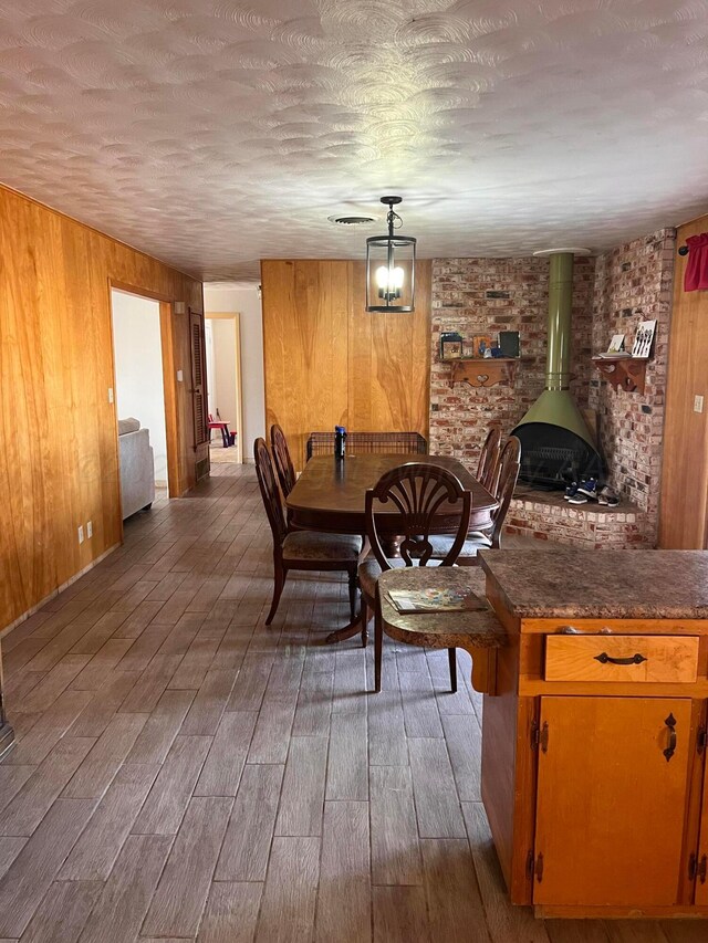 dining room with wooden walls, a wood stove, and wood finished floors