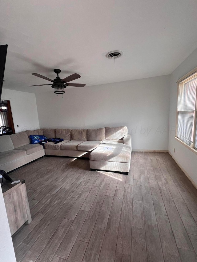 unfurnished living room with a ceiling fan, wood finished floors, and visible vents