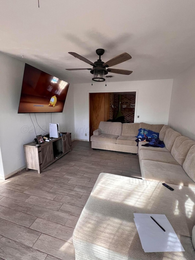 living area with wood finished floors, baseboards, and ceiling fan