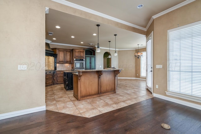 kitchen with a kitchen breakfast bar, arched walkways, an inviting chandelier, light wood-style flooring, and oven