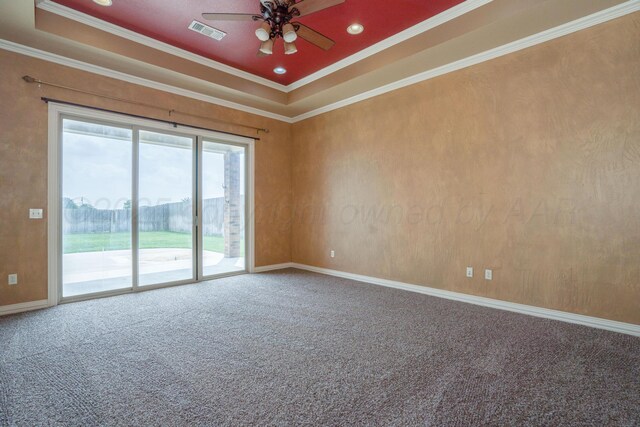 carpeted empty room featuring visible vents, ornamental molding, a raised ceiling, and a ceiling fan