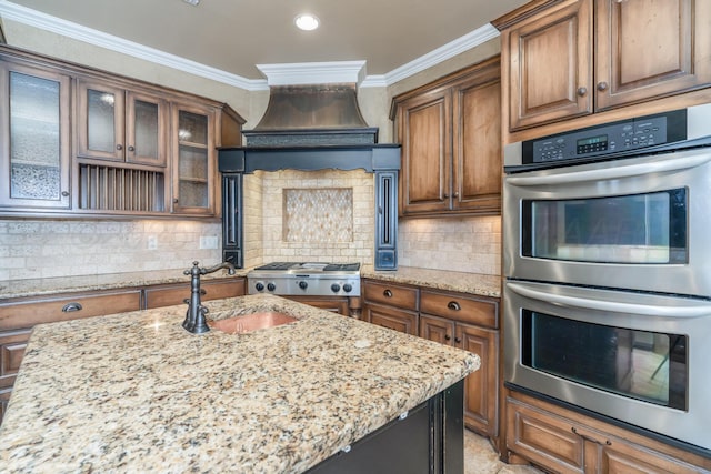 kitchen featuring light stone counters, a sink, stainless steel appliances, decorative backsplash, and ornamental molding