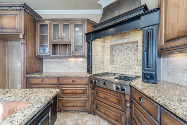 kitchen with crown molding, light stone counters, stainless steel gas stovetop, and tasteful backsplash