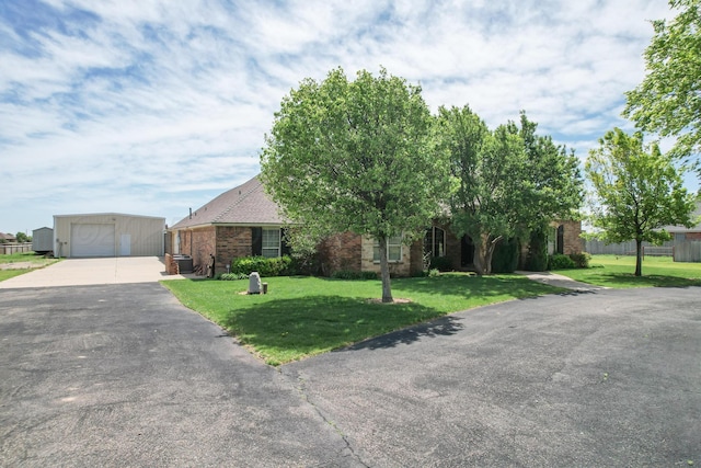 view of front facade with driveway, an outbuilding, a front lawn, and a garage