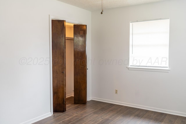 508 S Austin St, Shamrock, TX 79079 - unfurnished bedroom with dark wood-style flooring, a textured ceiling, a closet, and multiple windows