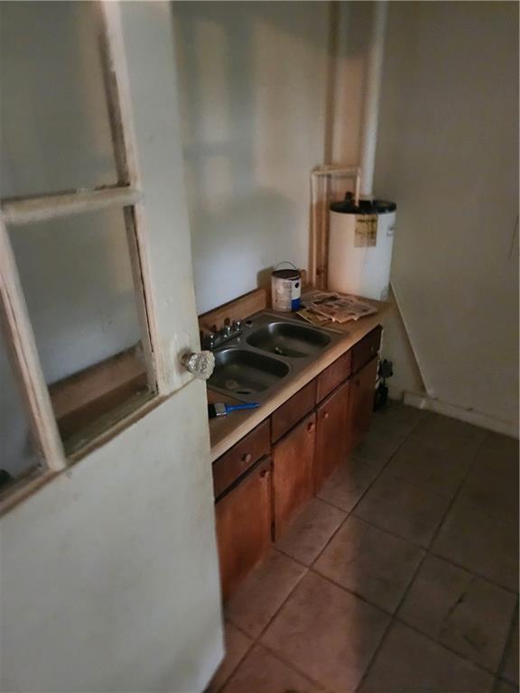 180 Carstens St, Mobile, AL 36617 - kitchen featuring water heater, light tile patterned floors, light countertops, and brown cabinetry