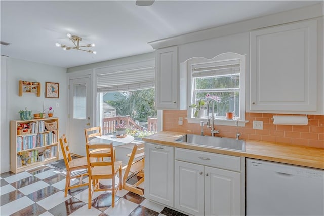 kitchen with a sink, dishwasher, light floors, white cabinetry, and tasteful backsplash