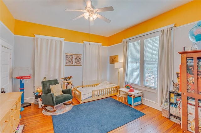 bedroom featuring a ceiling fan, multiple windows, and hardwood / wood-style flooring