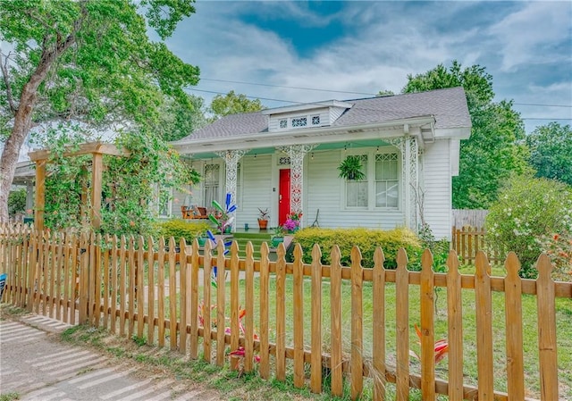 bungalow with a porch, a fenced front yard, and roof with shingles