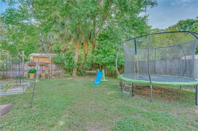 view of yard with a fenced backyard, a trampoline, and a vegetable garden