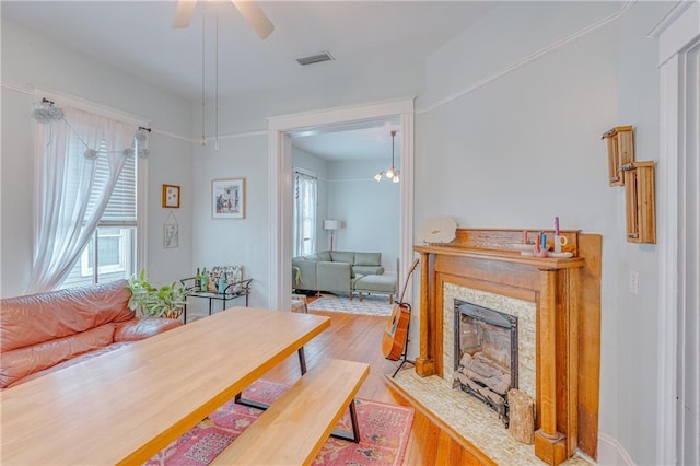living room with a ceiling fan, visible vents, wood finished floors, and a fireplace