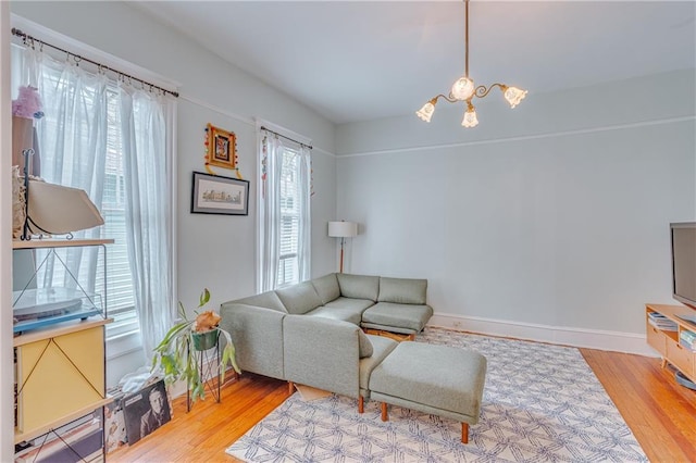 living area with baseboards, a notable chandelier, a healthy amount of sunlight, and wood finished floors