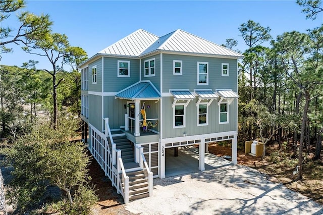 rear view of property with stairway, a standing seam roof, a carport, dirt driveway, and metal roof