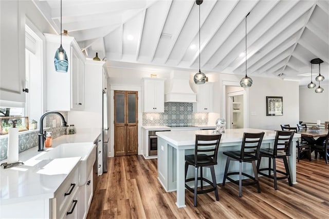 204 Magnolia Ct, Dauphin Island, AL 36528 - kitchen featuring custom exhaust hood, a sink, light countertops, white cabinets, and a kitchen breakfast bar