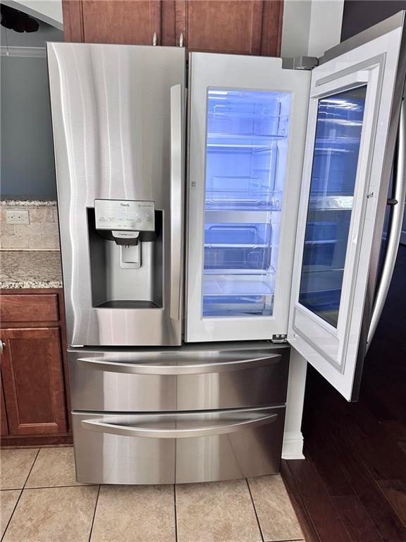 details with light stone countertops and stainless steel fridge with ice dispenser