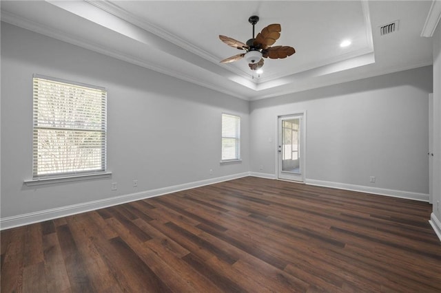 unfurnished room with crown molding, a tray ceiling, dark wood-type flooring, and ceiling fan