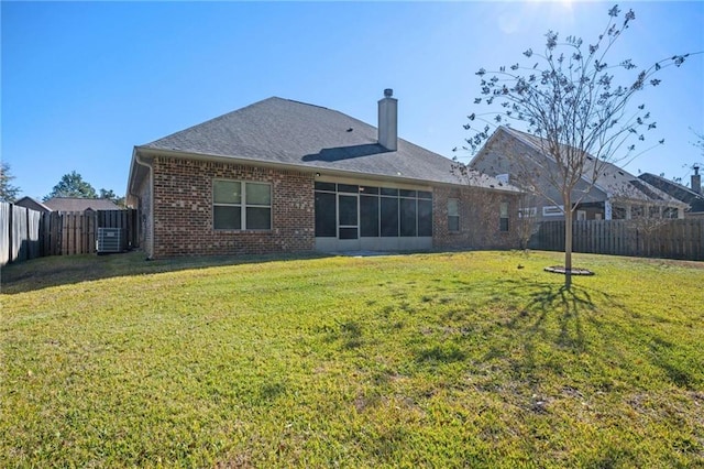 rear view of house with central AC unit and a lawn