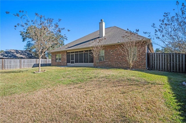 rear view of property with brick siding, a yard, and a fenced backyard