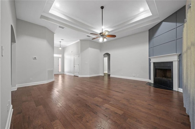 unfurnished living room featuring dark hardwood / wood-style floors, ceiling fan, a tray ceiling, and a tile fireplace