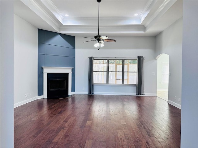 unfurnished living room with a tray ceiling, dark wood-type flooring, and ceiling fan