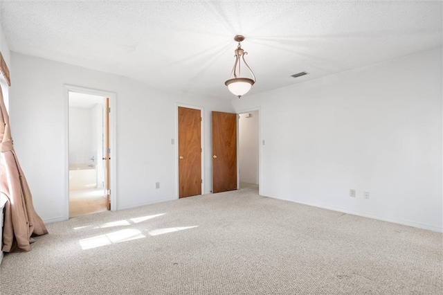 unfurnished bedroom with carpet floors, connected bathroom, and a textured ceiling