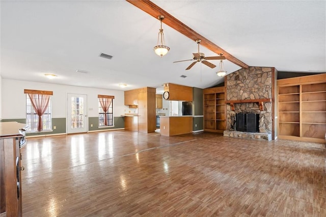 unfurnished living room featuring ceiling fan, vaulted ceiling with beams, dark hardwood / wood-style floors, built in shelves, and a stone fireplace