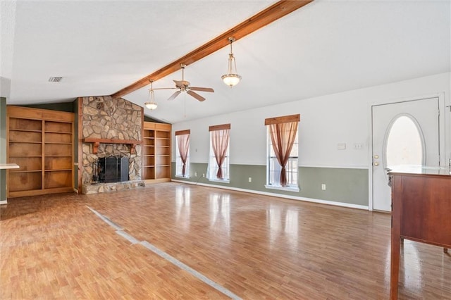 unfurnished living room featuring a stone fireplace, built in features, lofted ceiling with beams, hardwood / wood-style flooring, and ceiling fan