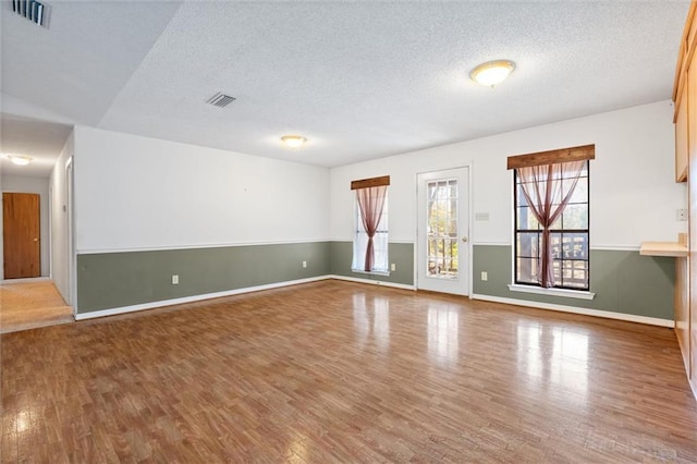 unfurnished room featuring hardwood / wood-style flooring and a textured ceiling