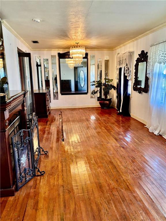 interior space featuring hardwood / wood-style floors, ornamental molding, and a chandelier