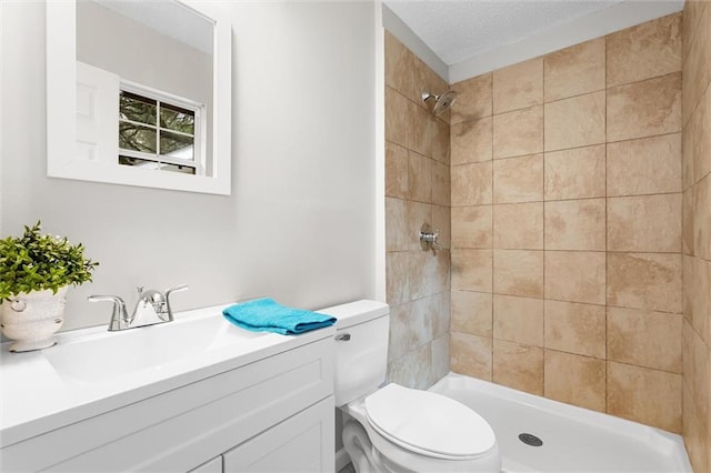 bathroom featuring vanity, toilet, a textured ceiling, and a tile shower