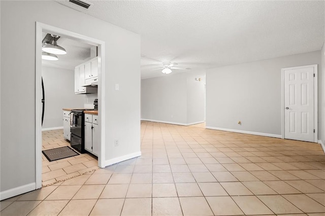 kitchen with light tile patterned floors, ceiling fan, white cabinetry, a textured ceiling, and black range with electric cooktop