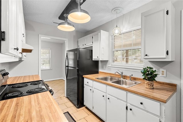 kitchen featuring pendant lighting, sink, white cabinetry, black refrigerator, and range with electric cooktop