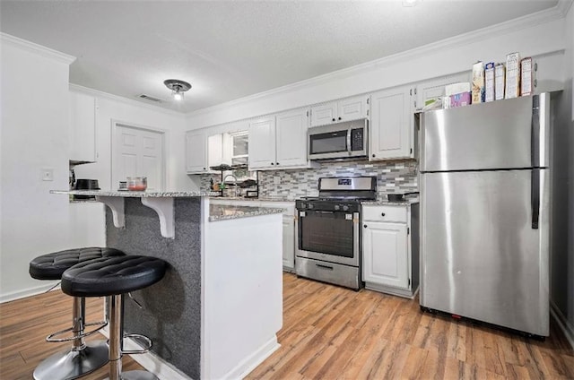 kitchen featuring light wood-type flooring, stainless steel appliances, light stone counters, and a breakfast bar