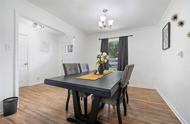 dining area with hardwood / wood-style flooring, ornamental molding, and a chandelier