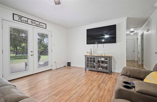 living room with ceiling fan, light hardwood / wood-style floors, crown molding, and french doors