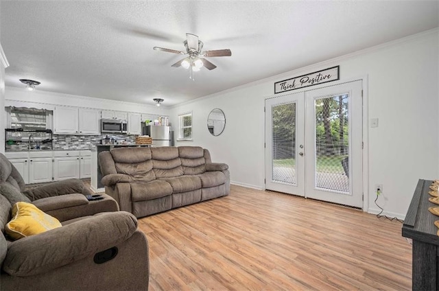 living room featuring ceiling fan, light hardwood / wood-style flooring, french doors, and ornamental molding