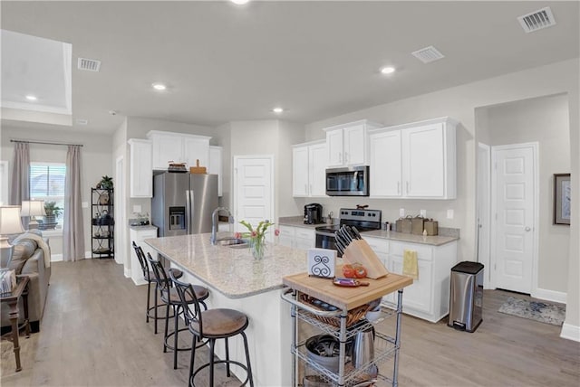 kitchen with light hardwood / wood-style floors, white cabinets, stainless steel appliances, and sink