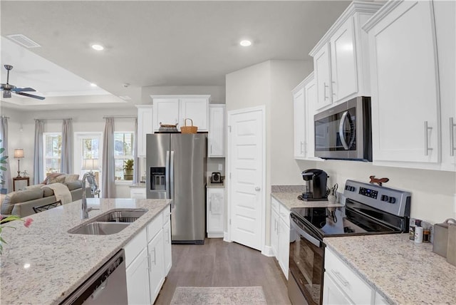 kitchen with appliances with stainless steel finishes, white cabinets, sink, and dark wood-type flooring