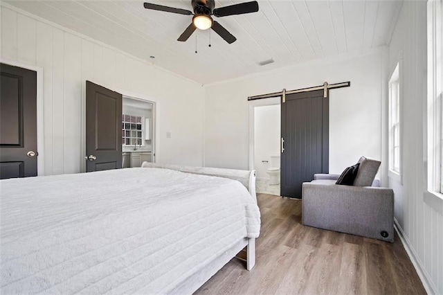 bedroom with ensuite bath, ceiling fan, a barn door, wooden ceiling, and light wood-type flooring