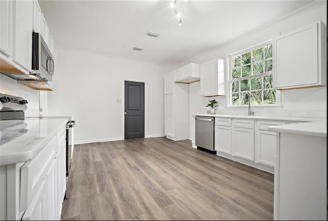 kitchen featuring appliances with stainless steel finishes, sink, light hardwood / wood-style floors, and white cabinets