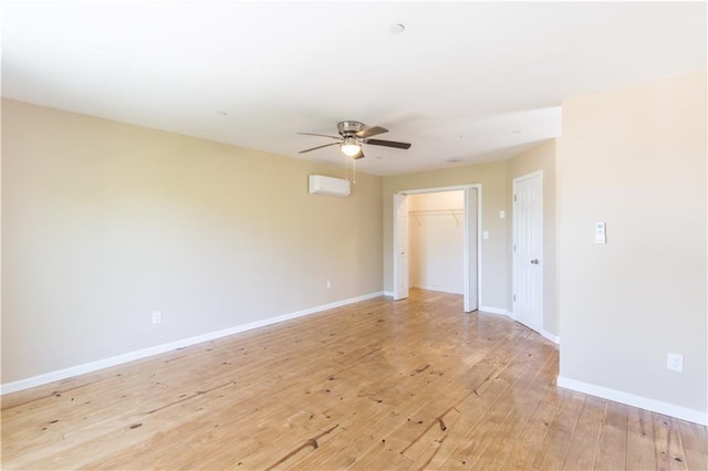 empty room with a wall unit AC, ceiling fan, and light wood-type flooring