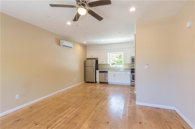 interior space with ceiling fan, light hardwood / wood-style floors, a wall mounted AC, and sink