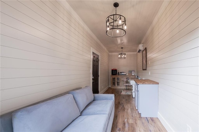 corridor with light wood-type flooring, a wall unit AC, and an inviting chandelier