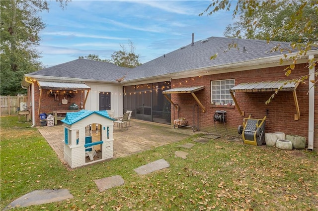 back of property featuring a sunroom, a patio, and a lawn