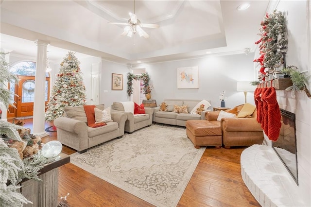 living room with ornate columns, ornamental molding, a raised ceiling, ceiling fan, and hardwood / wood-style floors